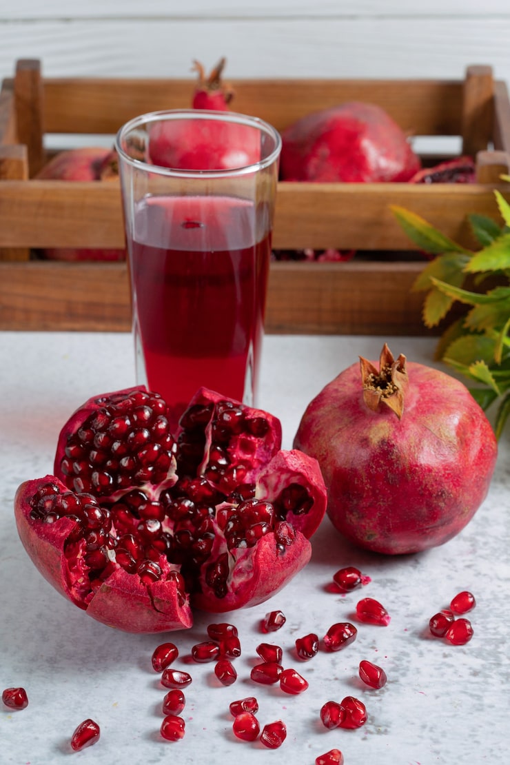 fresh-pomegranate-sliced-whole-with-glass-juice-grey-wall_114579-64088.jpg