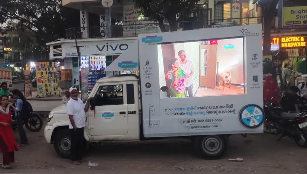 Mobile LED van running the Godrej Capital subsidy creative on a Gujarat market street