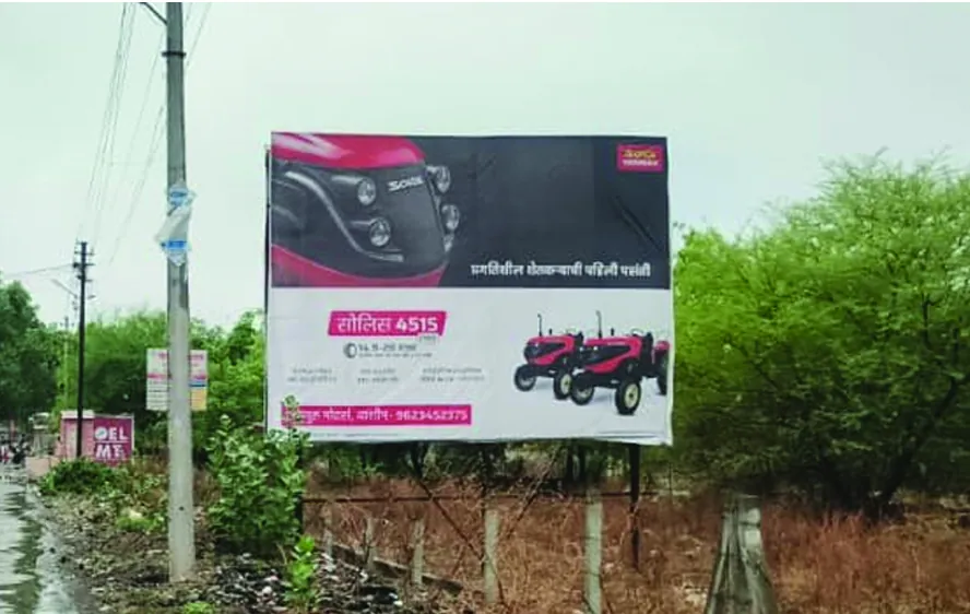 Solis 4515 hoarding in Marathi on a rural approach road, carrying the local dealer number